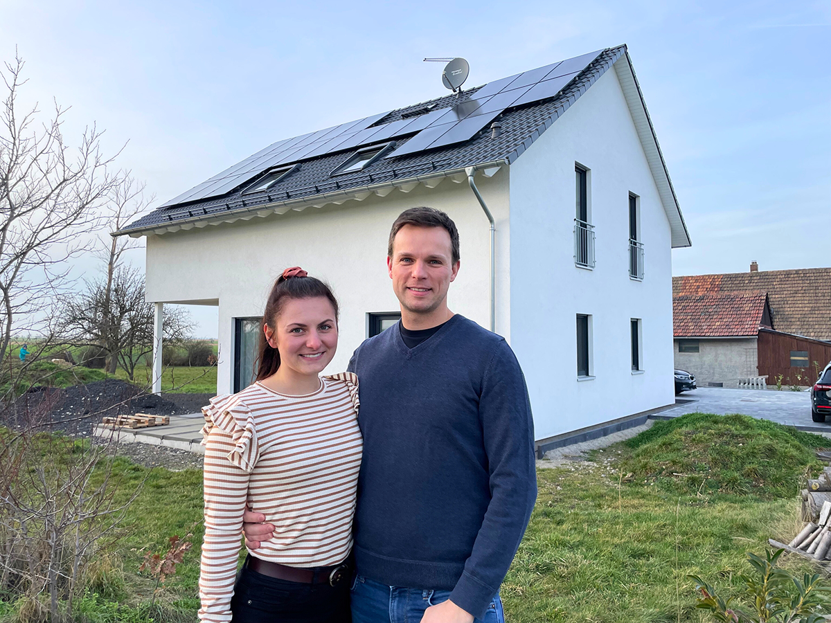 Ehepaar steht im Garten Ihres Hauses mit Solaranlage auf dem Dach