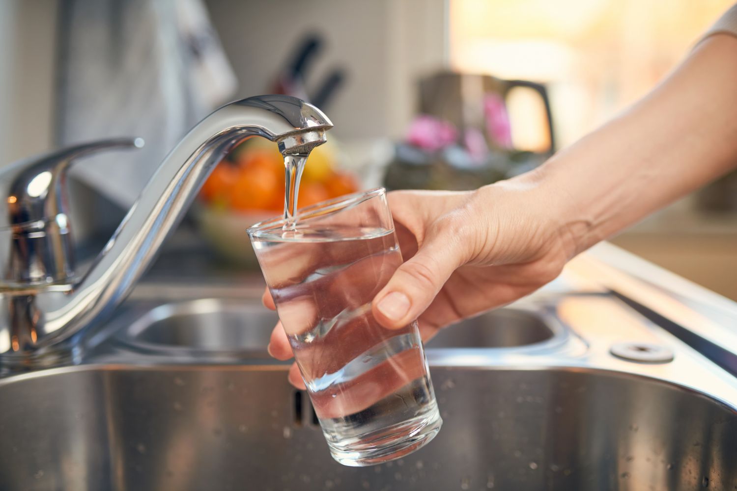 Ein Glas wird mit Trinkwasser an einem Wasserhahn in der Küche gefüllt.